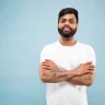 close-up-portrait-young-indian-man-white-shirt-posing-standing-smiling-looks-calm_155003-23821